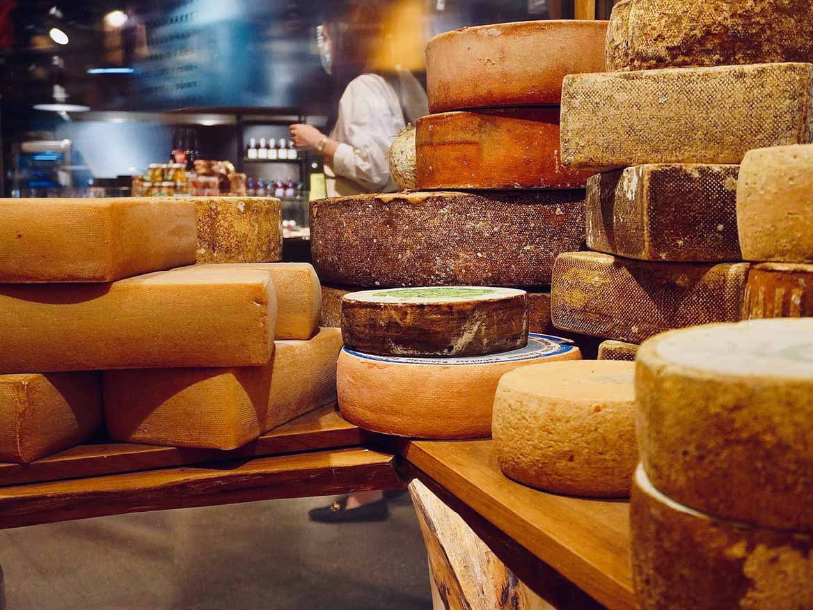 Wheels of aged cheese stacked on shelves in a cheese shop