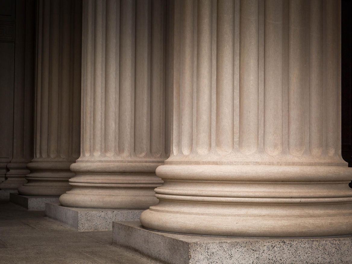 Close-up of tall classical stone columns along a government building