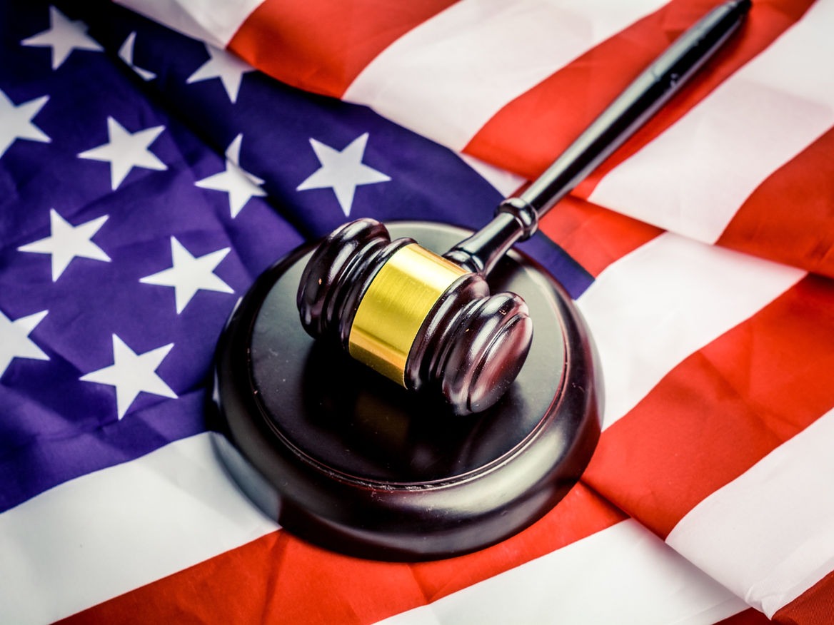 Wooden gavel on a sound block resting on an American flag