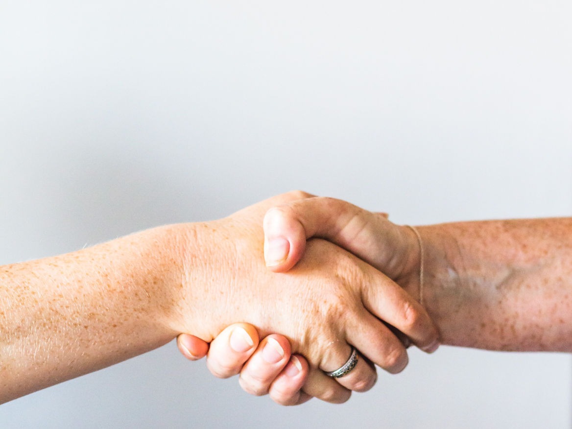 Close-up of two hands shaking against a white background