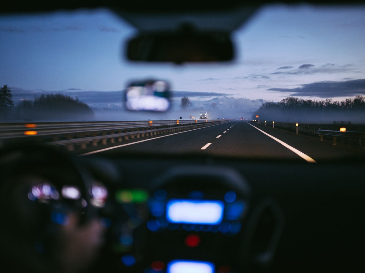 View of an open highway at dusk from a car dashboard