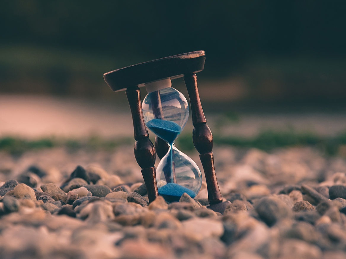Hourglass standing on pebbles with sand running through