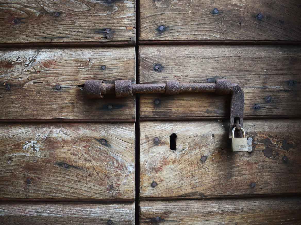 Padlock on a Wooden Door Rusty bolt and padlock on an old weathered wooden door
