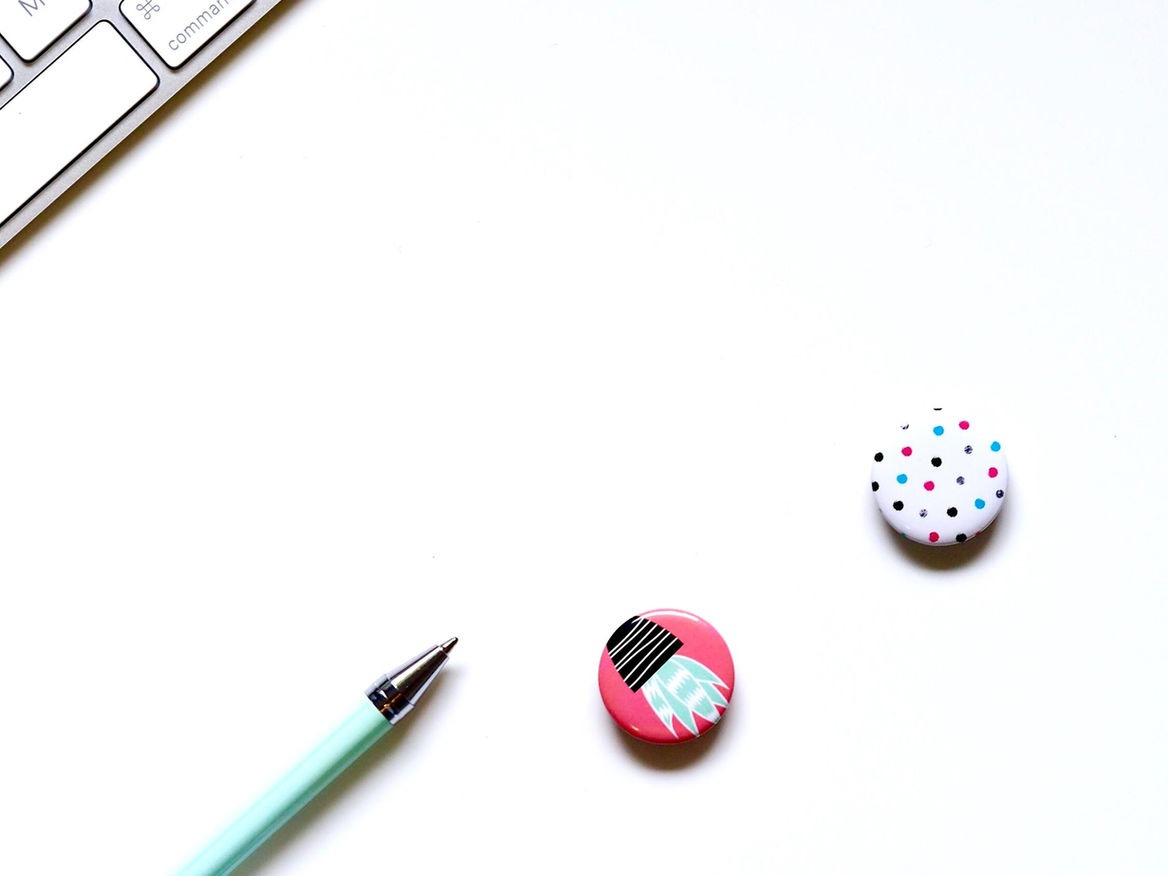 Minimal white desk with a pen and two decorative push pins
