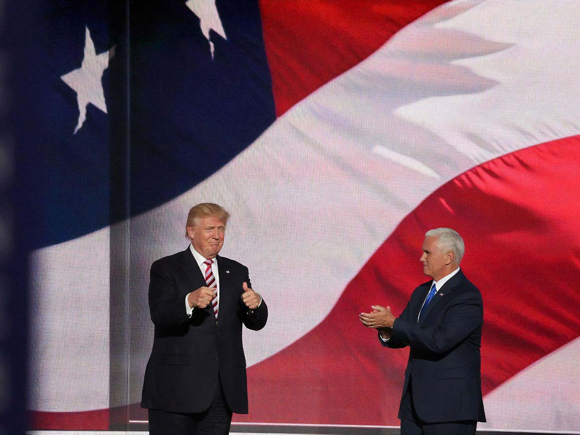 Donald Trump and Mike Pence on stage in front of a large American flag