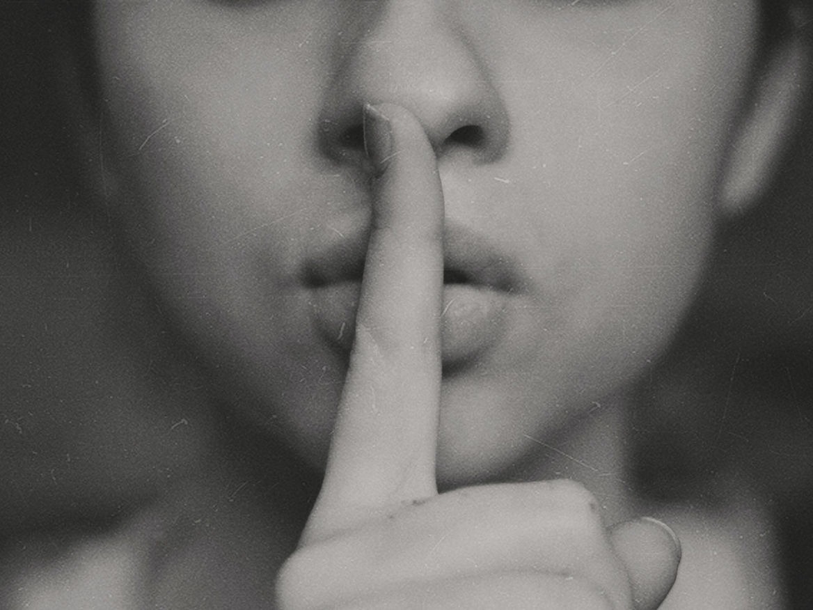 Black-and-white close-up of a woman holding a finger to her lips