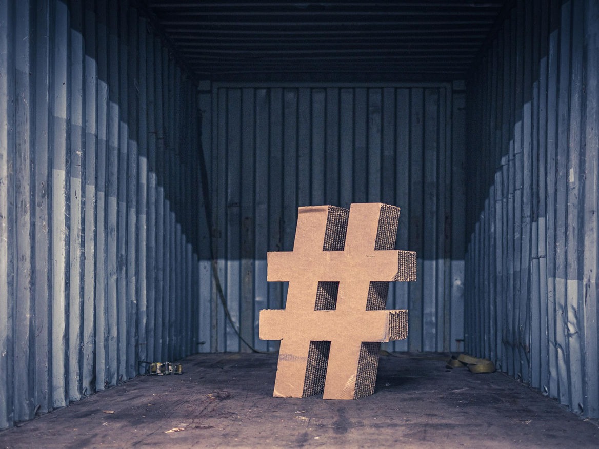 Large wooden hashtag symbol standing inside an empty shipping container